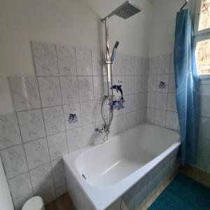a white tub in a bathroom with a blue shower curtain at Auszeitoase am Wald und Bach in Kradolf +12 photos
