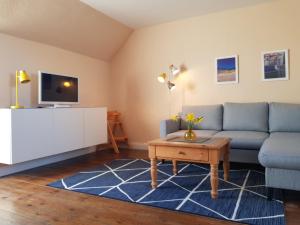 Una sala de estar con un sofá azul y una mesa. en Haus im Felde, en Fehmarn