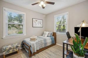 a bedroom with a bed and a table and windows at Murray Hill Bungalow in Jacksonville