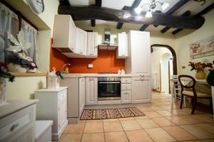 a kitchen with white cabinets and an orange wall at To Be Home in Bomarzo