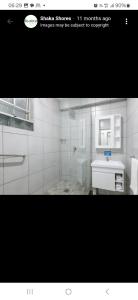 a white bathroom with a shower and a sink at Shaka Shores in Durban