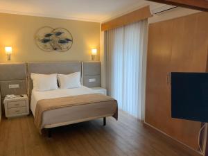 a bedroom with a bed and a flat screen tv at Hotel Mare in Nazaré +37 photos