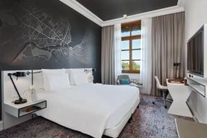 ein Hotelzimmer mit einem großen weißen Bett und einem Schreibtisch in der Unterkunft Hôtel Métropole Genève in Genf