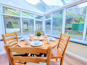 a dining room with a table and chairs and windows at Waterwitch Cottage in Newquay