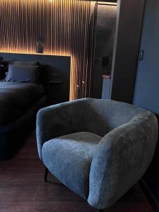 a living room with a blue chair and a bed at Osmose Dijon in Dijon