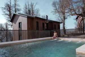 a woman sitting on the edge of a swimming pool at RentUp - Escapate a la Montana, Vila de lujo en San Martin de los Andes in San Martín de los Andes