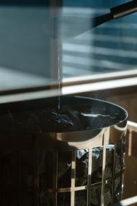 a pot with water being poured into an oven at 富士山望むプライベートヴィラ 900平方メートルの敷地を貸切利用 憩 ikoi Fuji サウナ 4Kシアター in Fujikawaguchiko