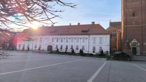 a large white building with a clock tower next to a street at Vintage in Đakovo