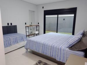 une chambre avec deux lits et une grande fenêtre dans l'établissement Nosso Recanto 2 Próximo aos Pontos Turísticos, à Foz do Iguaçu