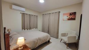 a bedroom with a white bed and a chair at My Shelter in Willemstad