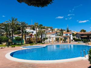 a large swimming pool with palm trees and houses at Chalet Estibaliz unifamiliar in Peniscola