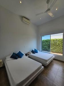 two beds in a room with a large window at Girardot Casa estilo mediterraneo con piscina privada in Girardot +36 photos