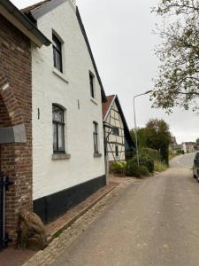 a white building with windows on the side of a street at boerderij, voorhuis in Schimmert