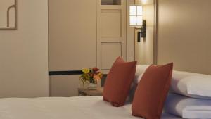 a bed with two pillows and a vase with flowers on it at Calaserena Resort in Geremèas