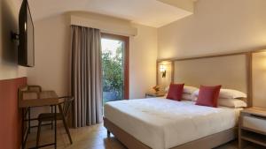 a hotel room with a large bed and a window at Calaserena Resort in Geremèas