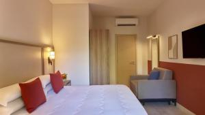 a hotel room with a white bed and a chair at Calaserena Resort in Geremèas