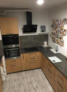 Una cocina con gabinetes de madera y una encimera negra. en Zielony Tarchomin, en Varsovia