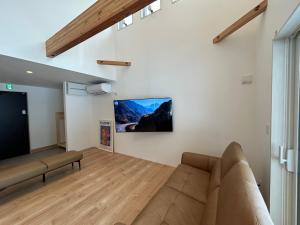 a living room with a couch and a flat screen tv at Kokoro House Misorano in Hakuba