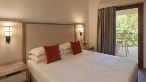 a bedroom with a large white bed and a balcony at Calaserena Resort in Geremèas
