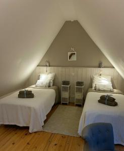 a attic bedroom with two beds and a blue chair at Longère Normande in Sainte-Marguerite