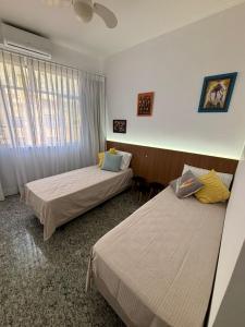 a hotel room with two beds and a window at Espaçoso e iluminado, 1 quadra da praia, ar condicionado in Rio de Janeiro