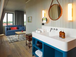 a bathroom with a sink and a blue couch at 25hours Hotel Paper Island in Copenhagen +59 photos