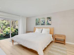 ein weißes Schlafzimmer mit einem großen Bett und einem Fenster in der Unterkunft Charming Two-King-bedroom house in delightful Naples in Naples