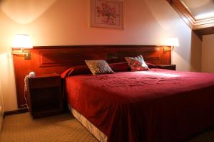 a bedroom with a red bed with two pillows at Hotel Reviens in Pinamar