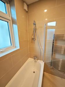 a bathroom with a bath tub and a shower at Bright and Spacious 2-Bedroom Flat Near Emirates Stadium in London