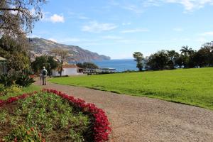 a man walking down a path next to a field of flowers at São Francisco Accommodation in Funchal