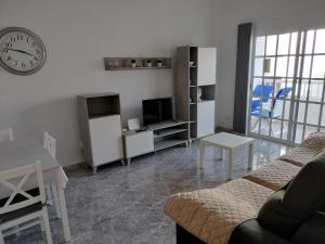 a living room with a couch and a table and a clock at Casa Esperanza in Arinaga