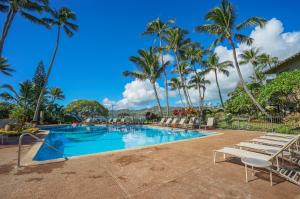 a swimming pool with chairs and palm trees at "Bay Watch" at Lae Nani 335- 2 Bedroom Ocean View Condo with AC in Kapaa