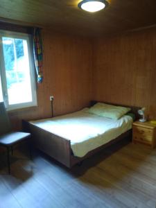 a bedroom with a bed and a chair and a window at Ferien Cottage Flüehblüemli in Stechelberg