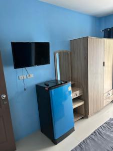 a room with a small refrigerator and a tv on the wall at Mildmint มายมิ้นท์อพาร์ทเม้นท์ Self Serviced in Kata Beach