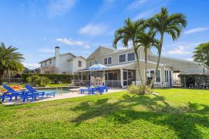 Una casa con un patio con sillas azules y palmeras. en Cape Lake House Lake Front, en Lochmoor Waterway Estates