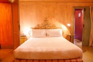 a bedroom with a white bed with a wooden headboard at Casa Baladin camere di Charme in Piozzo +49 photos