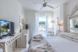 biały pokój z łóżkiem i telewizorem w obiekcie Il San Francesco Charming Hotel w mieście Sabaudia
