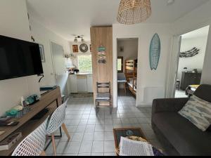 a living room with a couch and a tv and a kitchen at 5 min du village de Noël Barcarès mas de pêcheurs 8 couchages tout confort in Le Barcarès