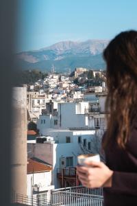 a woman standing on a balcony looking at a city at Bill Apartments in Patra