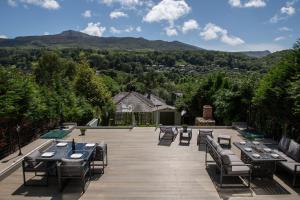 a patio with tables and chairs with mountains in the background at Eryri Snowdonia Premier Family Retreat with Hot Tub and Fire Pit in Dolgellau