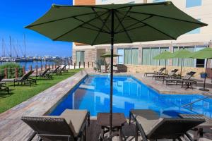 a pool with a green umbrella and chairs and a table at Courtyard by Marriott La Paz Baja California Sur in La Paz