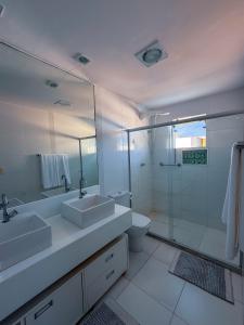 a bathroom with two sinks and a shower and a toilet at 230m da PRAIA, casa com ESPAÇO GOURMET e CHURRASQUEIRA, Portaria 24h, 2 VAGAS de GARAGEM, acomoda até 10 PESSOAS, Próximo a MERCADOS e FARMÁCIA in Salvador