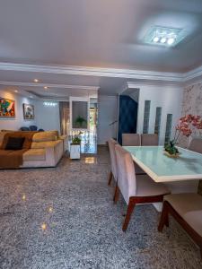 a living room with a couch and a table at 230m da PRAIA, casa com ESPAÇO GOURMET e CHURRASQUEIRA, Portaria 24h, 2 VAGAS de GARAGEM, acomoda até 10 PESSOAS, Próximo a MERCADOS e FARMÁCIA in Salvador +17 photos