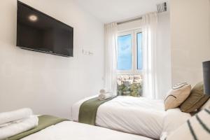 a white room with two beds and a flat screen tv at Panoramic skyrise on the 20th floor by REMS in Málaga +38 photos
