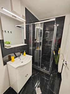 a black and white bathroom with a sink and a shower at Casa De Sub Padure in Bran