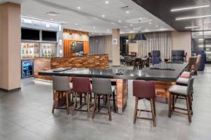 奥克莫斯Courtyard by Marriott East Lansing Okemos的大堂设有酒吧,周围摆放着椅子