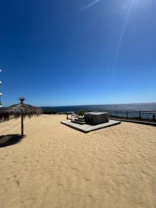 a beach with an umbrella and benches and the ocean at Apartamento Cielo y Mar in Yeco +17 photos