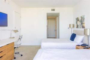 Una habitación de hotel con dos camas y un escritorio. en Luxury Suite on Beachwalk with Pool Gym & Beach, en Hallandale Beach