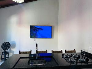 a kitchen with a table and a tv on the wall at Vila Limeira in Porto Seguro