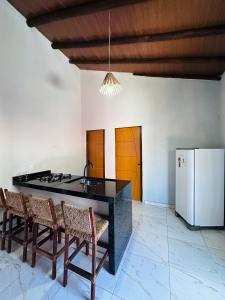 Vila Limeira في بورتو سيغورو: مطبخ مع كونتر اسود مع كراسي وثلاجة